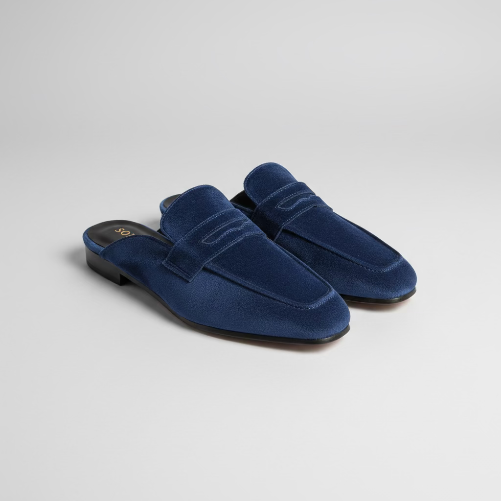 A pair of navy blue suede slip-on loafers with a strap across the instep, 